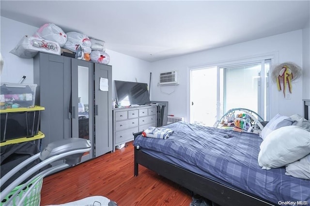 bedroom with an AC wall unit and dark wood-type flooring