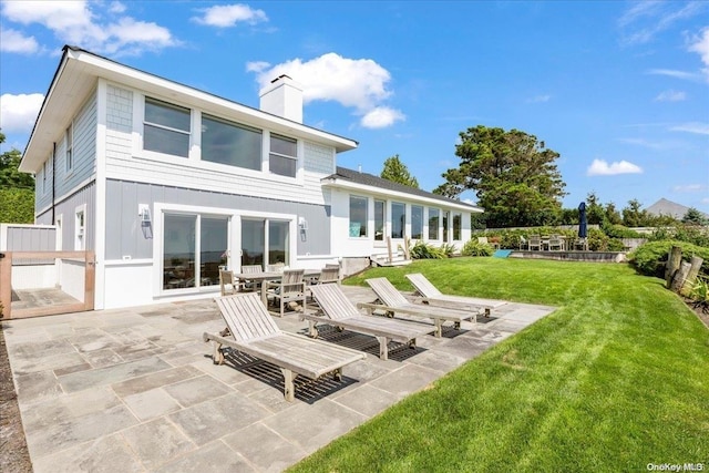 rear view of house featuring a lawn and a patio