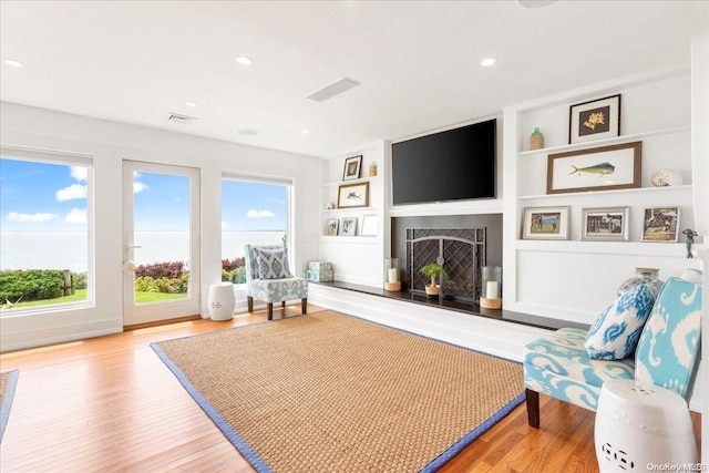 sitting room with built in features and light hardwood / wood-style flooring