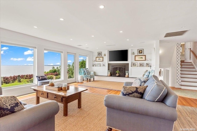 living room featuring built in features and light wood-type flooring