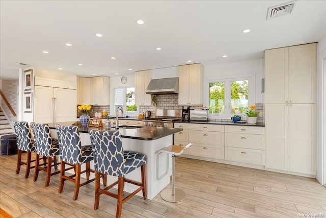 kitchen featuring light wood-type flooring, range hood, a healthy amount of sunlight, and sink