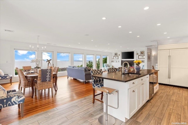 kitchen with white cabinetry, sink, light hardwood / wood-style floors, and decorative light fixtures