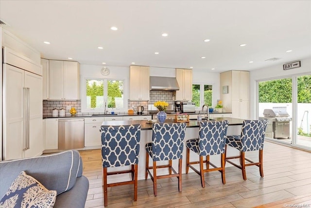 kitchen featuring dishwasher, light hardwood / wood-style flooring, extractor fan, and a wealth of natural light