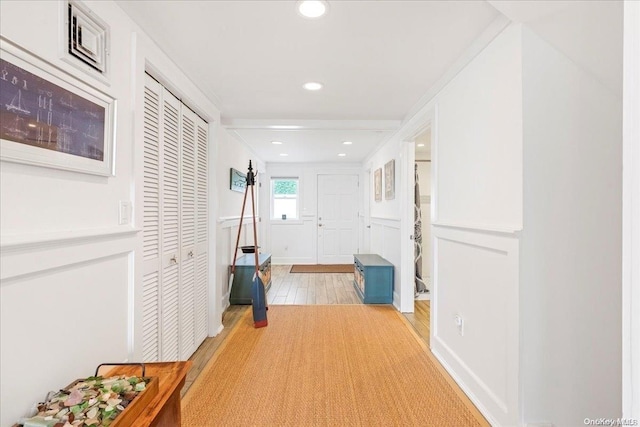 hallway with light wood-type flooring and ornamental molding