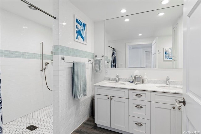 bathroom featuring wood-type flooring, vanity, and a tile shower