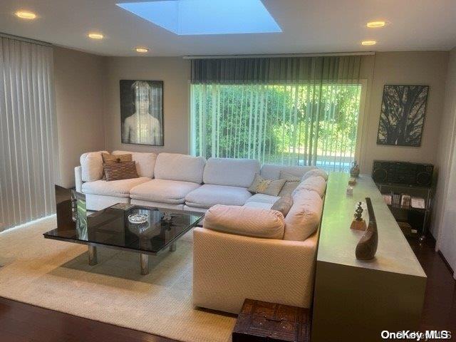 living room with plenty of natural light, hardwood / wood-style floors, and a skylight