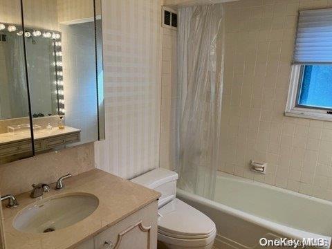 full bathroom with toilet, vanity, and shower / bath combination with curtain