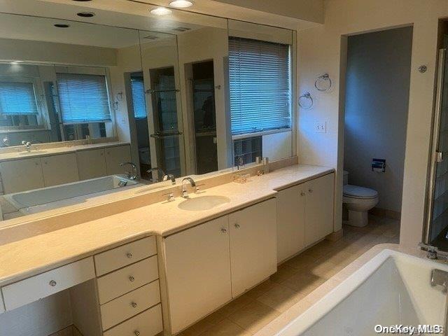 bathroom with toilet, vanity, a bathtub, and tile patterned flooring