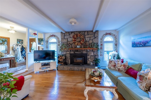 living room with hardwood / wood-style floors, a stone fireplace, and beamed ceiling