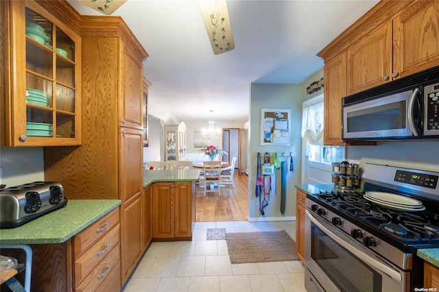 kitchen with hanging light fixtures, light hardwood / wood-style floors, kitchen peninsula, stainless steel appliances, and a chandelier