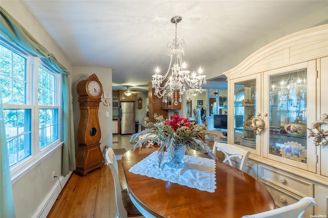 dining room with baseboard heating, light hardwood / wood-style flooring, and ceiling fan with notable chandelier