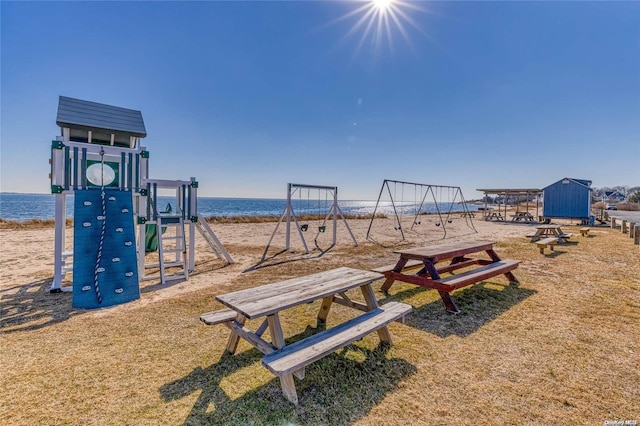 view of jungle gym featuring a water view and a beach view