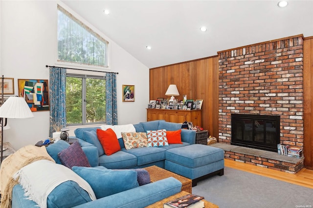 living room with a fireplace, hardwood / wood-style flooring, high vaulted ceiling, and wooden walls