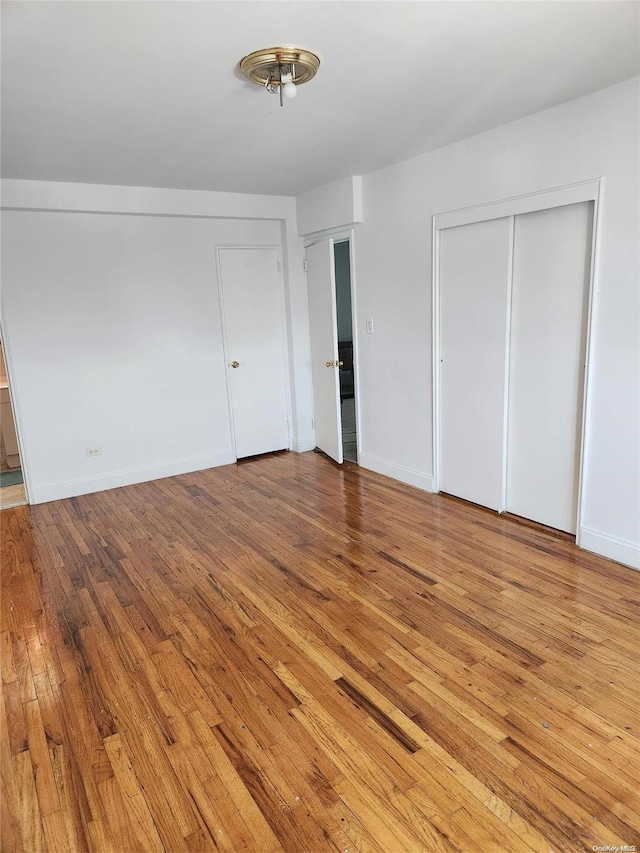 unfurnished bedroom with two closets and light hardwood / wood-style flooring