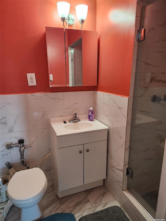 bathroom with vanity, a shower with shower door, and tile walls