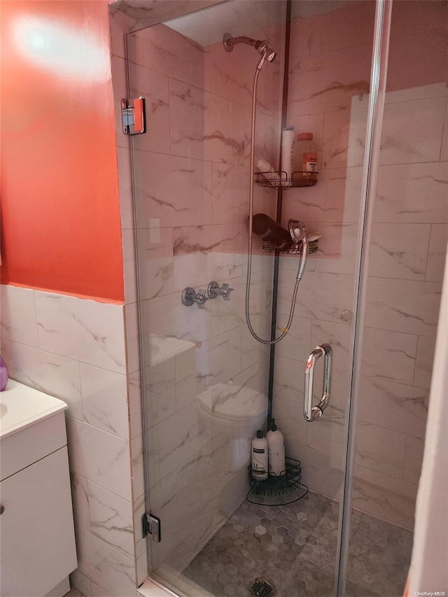 bathroom with vanity, a shower with door, and tile walls