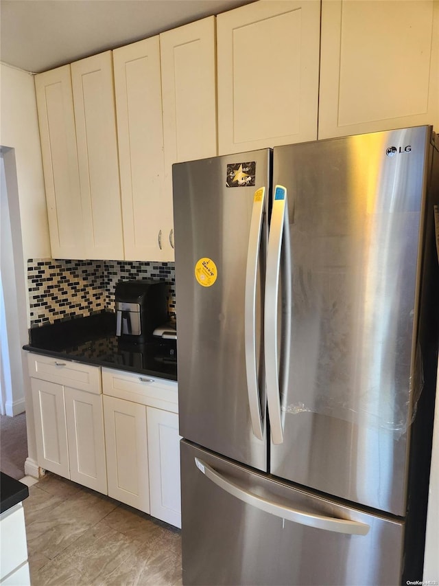 kitchen featuring backsplash, stainless steel fridge, and white cabinetry