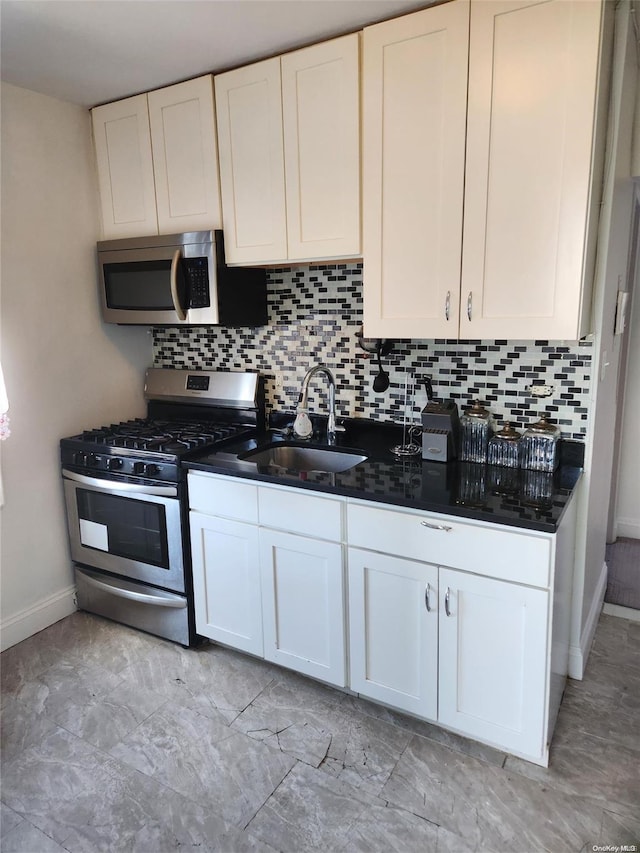 kitchen with decorative backsplash, appliances with stainless steel finishes, white cabinetry, and sink