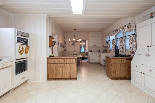 kitchen with pendant lighting, a center island, an inviting chandelier, double oven, and kitchen peninsula