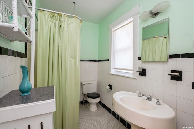 bathroom with tile patterned floors, plenty of natural light, toilet, and tile walls