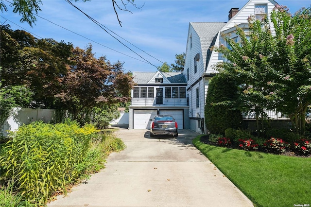 view of front of property with a front yard, a garage, and a sunroom