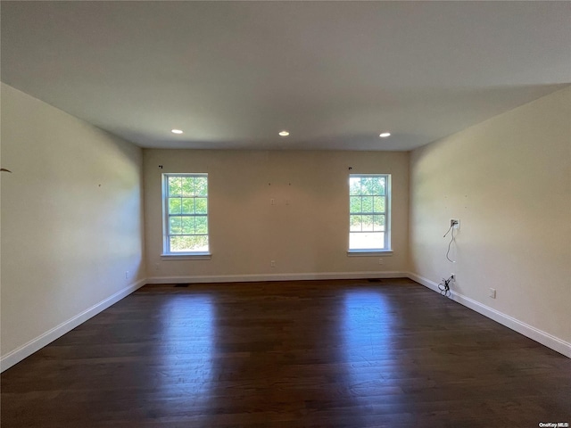 empty room featuring plenty of natural light and dark hardwood / wood-style floors