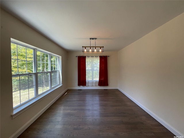 unfurnished dining area featuring an inviting chandelier and dark wood-type flooring