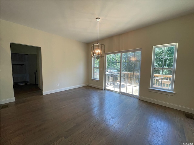 spare room featuring dark hardwood / wood-style floors and an inviting chandelier