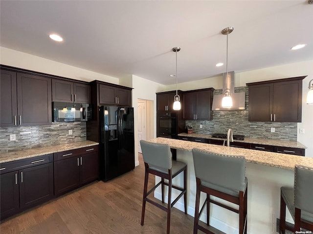 kitchen with black appliances, a kitchen breakfast bar, pendant lighting, and dark wood-type flooring