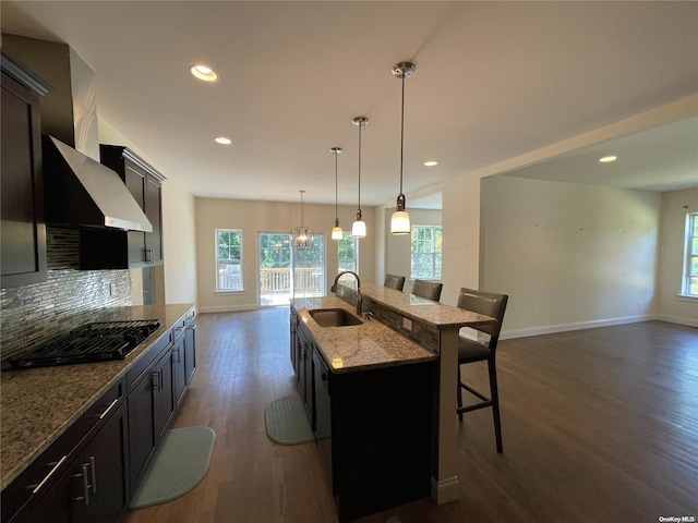 kitchen with sink, gas stovetop, dark hardwood / wood-style flooring, an island with sink, and a breakfast bar area