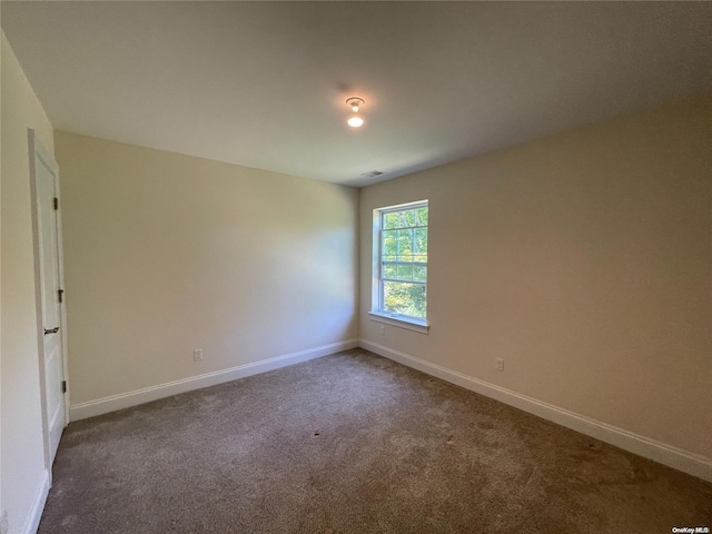 unfurnished room featuring dark colored carpet