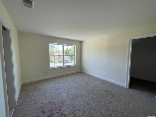 unfurnished bedroom with carpet flooring, a walk in closet, and a closet