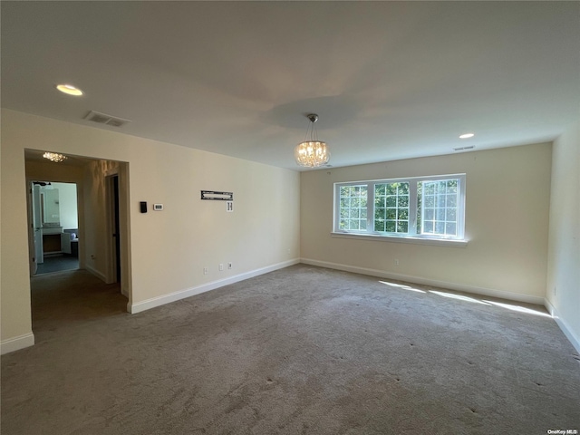 unfurnished room with a chandelier and dark colored carpet