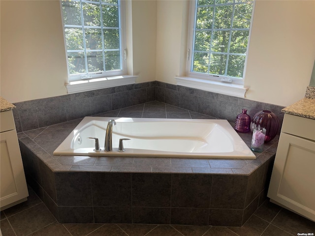 bathroom with tile patterned floors, tiled bath, and vanity