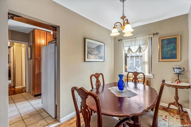 dining space with light hardwood / wood-style floors and a notable chandelier