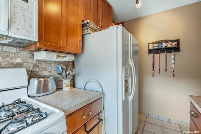 kitchen featuring decorative backsplash, light tile patterned flooring, and white appliances