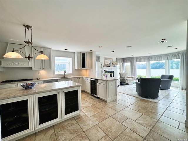 kitchen featuring backsplash, gas stovetop, beverage cooler, an inviting chandelier, and hanging light fixtures