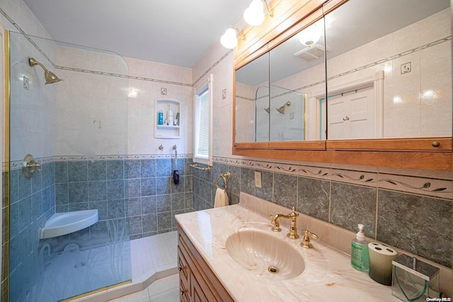 bathroom featuring a tile shower, vanity, and tile walls