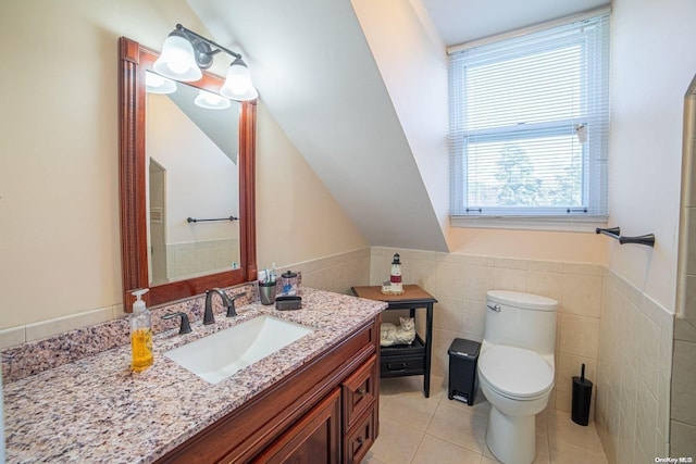 bathroom featuring toilet, vanity, tile patterned floors, and tile walls