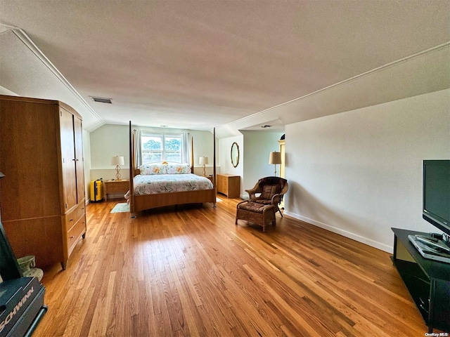 bedroom with lofted ceiling, light wood-type flooring, and a textured ceiling