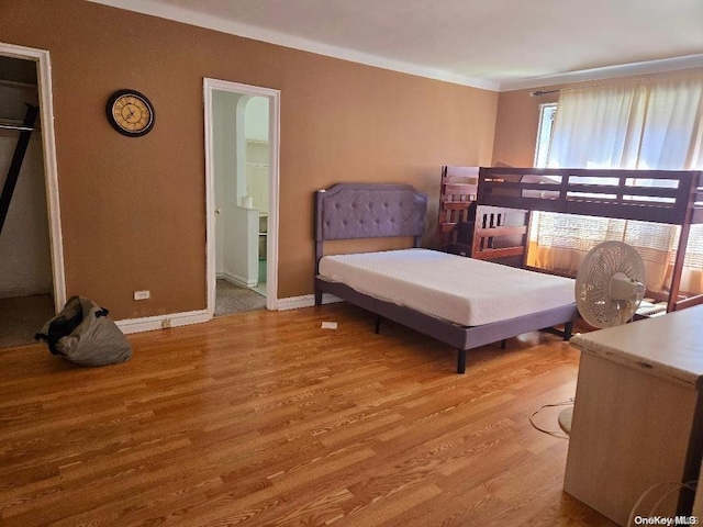 bedroom with connected bathroom and light hardwood / wood-style floors