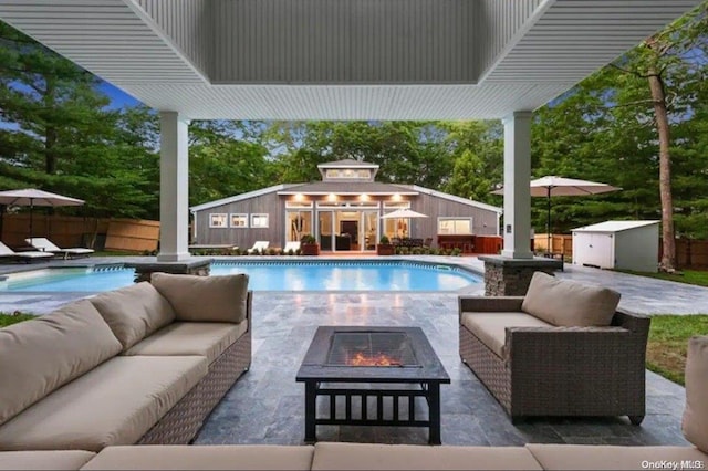 view of swimming pool featuring an outbuilding, a patio, and an outdoor living space with a fire pit