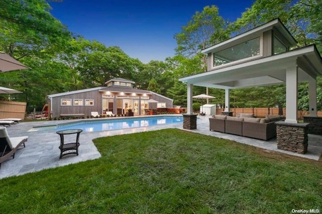 view of pool featuring a lawn, outdoor lounge area, a patio area, and an outbuilding