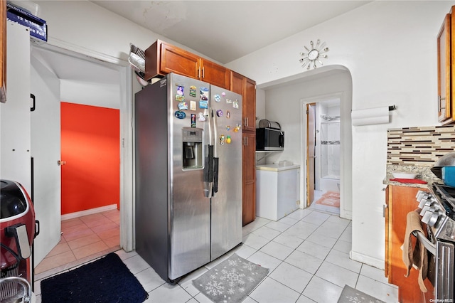 kitchen featuring light tile patterned flooring, washer / dryer, stainless steel appliances, and tasteful backsplash