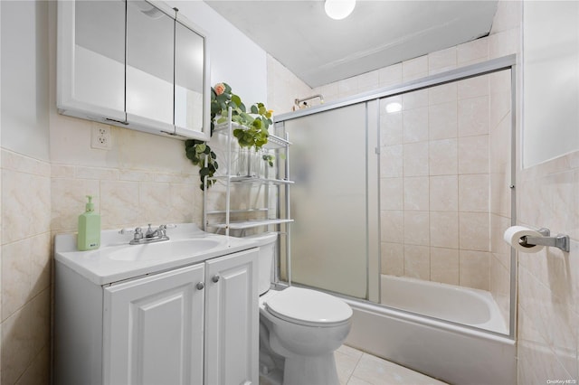 full bathroom with tile patterned flooring, bath / shower combo with glass door, toilet, vanity, and tile walls