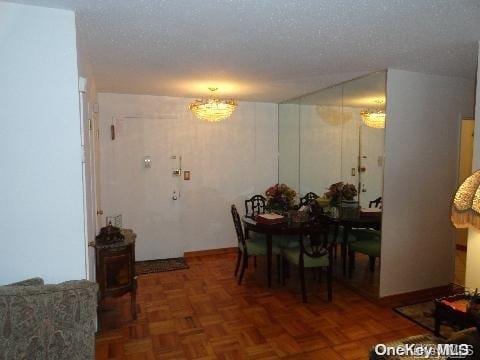 dining room featuring a notable chandelier, dark parquet flooring, and a textured ceiling