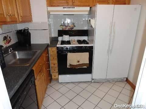 kitchen with light tile patterned floors, white appliances, tasteful backsplash, and sink