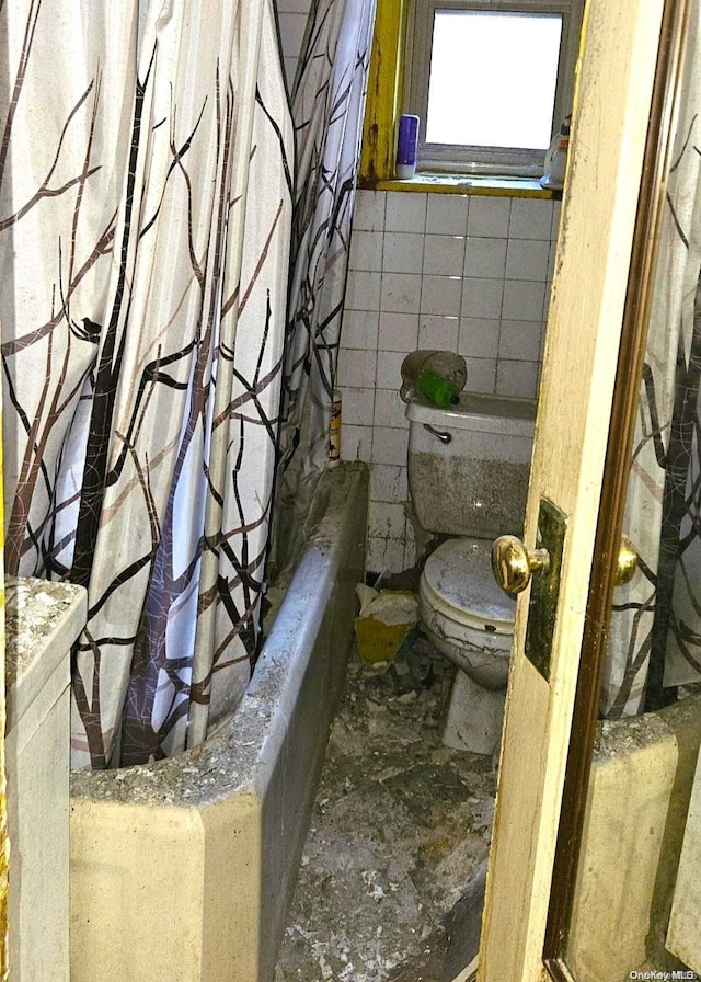 bathroom with shower / bathtub combination with curtain, toilet, and tile walls