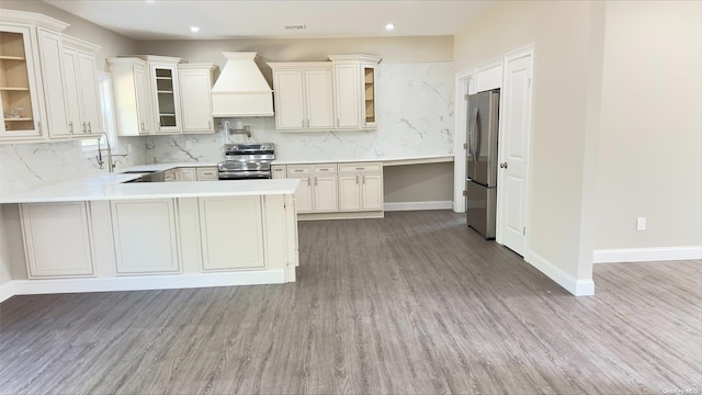 kitchen featuring hardwood / wood-style floors, sink, custom range hood, kitchen peninsula, and stainless steel appliances