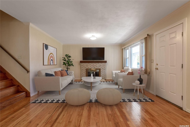 living room with a fireplace, crown molding, and light hardwood / wood-style flooring